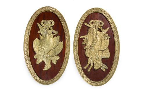 240   -  <p><span class="object_title">Pareja de decorativos paneles ovales de estilo Luis XVI con relieves de motivos de caza, a modo de trofeos, y orlas en bronce dorado sobre soporte en madera. Francia, C. 1900.</span><br></p>
