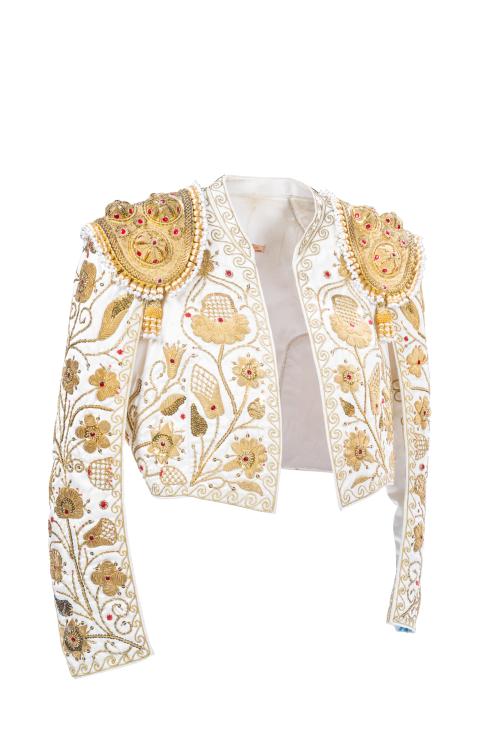 <p><span class="object_title">JUSTO ALGABA, "Sastre de Toreros", Madrid.<br/>Chaquetilla de alternativa confeccionada como prenda femenina para evento. <br/>En seda blanca con canutillo de oro formando flores y piñas y caireles rematados en símil de perlas. Aplicaciones de cristales en rojo rubí. </span><br></p>
