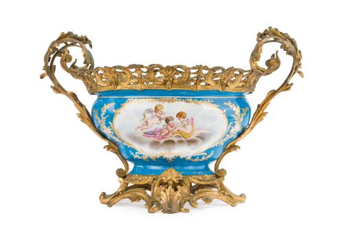 231 - <p><span class="object_title">Jardinera en porcelana de estilo Sèvres, Francia, C. 1900.<br/>En porcelana azul celeste con decoraciones esmaltadas de flores y angelotes en reservas con detalles en dorado.</span><br></p>