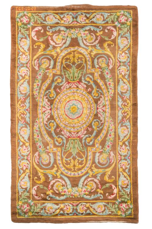 90 - <p><span class="object_title">Alfombra española en lana, Fundación de Gremios. Firmada y fechada en 1949.<br/>Con decoración de guirnaldas florales y motivos vegetales con florón central sobre campo marrón. </span><br></p>