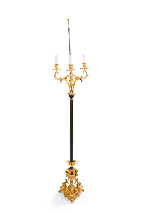 316 - <p><span class="object_title">Lámpara de pie con tres brazos de luz en bronce dorado y pavonado con fuste de columna estriada sobre base vegetal con conchas y hojas de acanto.</span><br></p>