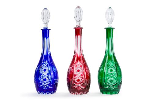 313 - <p><span class="object_title">Lote de tres licoreras en cristal de Bohemia moldeado y tallado a rueda con decoración de racimos de uvas y hojas en tontos rojo rubí, verde y azul cobalto. </span><br></p>