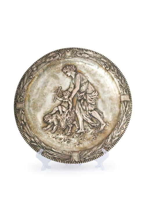 253   -  <p><span class="object_title">Gran plato decorativo en plata, posiblemente francés, ff. S. XIX. <br/>Decoración de escena mitológica en el campo y alero cincelado con decoración de hojas de laurel. Perímetro con acanaladuras. Con marcas. </span><br></p>