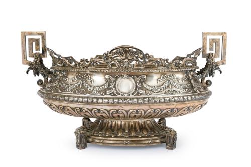 93 - <p><span class="object_title">Gran centro de mesa en plata portuguesa punzonada, de forma oval, con profusa decoración cincelada de motivos vegetales con guirnaldas de flores con lazos y ovas. Perímetro superior calado y asas geométricas.</span><br></p>