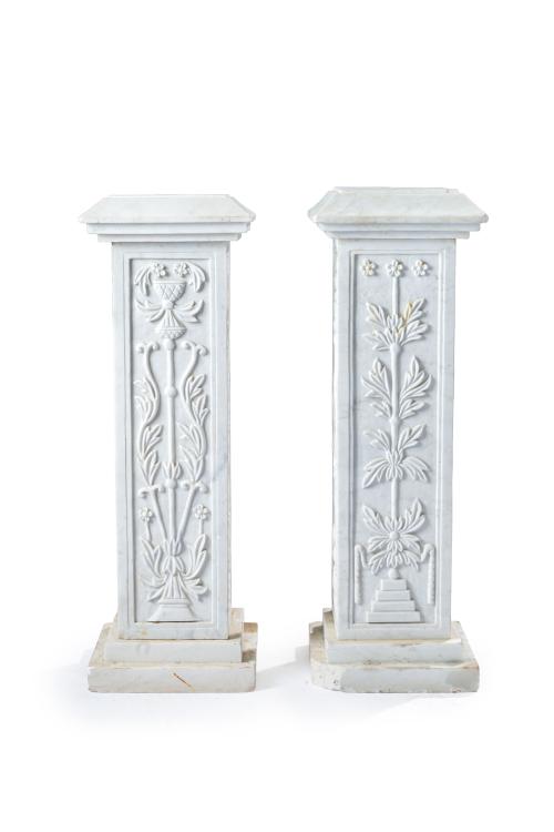 18 - <p><span class="object_title">Pareja de peanas de exterior en mármol blanco tallado con frentes decorados con motivos neoclásicos. Sobre base escalonada. </span><br></p>