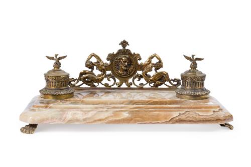 599   -  <p><span class="object_title">Gran escribanía en ágata con frente en bronce dorado, C. 1900.<br/>Con doble tintero rematados en águilas y soporte para plumas. Sobre patitas de garra. </span><br></p>