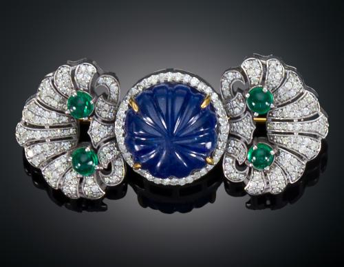 949 - <p><span class="object_title">BROCHE CON TANZANITA CENTRAL GALLONADA FLANQUEADA POR VENERAS CON DIAMANTES Y ESMERALDAS EN CABUJÓN</span></p>