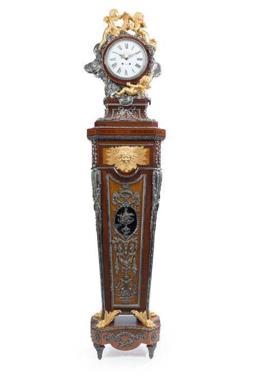 905   -  <p><span class="object_title">Impotrante reloj de pedestal estilo Napoleón III, Francia, ppios. S. XX<br/>Siguiendo modelos de Jean Henri Riesener (Francia, 1734-1806)<br/>En madera de palo rosa, madera de caoba, madera frutal y fileteado de boj. Con aplicaciones en bronce dorado y bronce plateado de gusto neoclásico. Laterales con marquetería de "losangée"<br/>Caja arquitectónica, mascarón solar y motivos vegetales. Remate superior con reloj circualr esmaltado y flanqueado por querubines dorados. Esfera en porcelana con numeración romana y maquinaria tipo Morbier. </span><br></p>