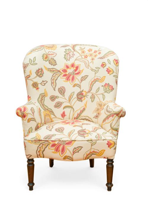 Sillón tapizado en beige con motivos florales. 