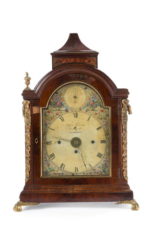 16   -  <p><span class="object_title">Reloj bracket georgiano , c. 1800. John Thwaites Clerkenwell, Londrés.<br/>En madera de caoba, caja arquitectónica de frente en arco de medio punto y remate superior en forma de pabellón. Decoración aplicada en bronce dorado con motivos vegetales y rocallas. <br/>Apoya sobre cuatro patas en voluta en bronce dorado. Esfera pintada con numeración romana, decoración floral polícroma y representación de jarrones con flores y pájaros. <br/>Firmada "Jno Thwaites Clerkenwell, Londres"<br/>Movimiento mecánico de cuerda con sonería. </span><br></p>
