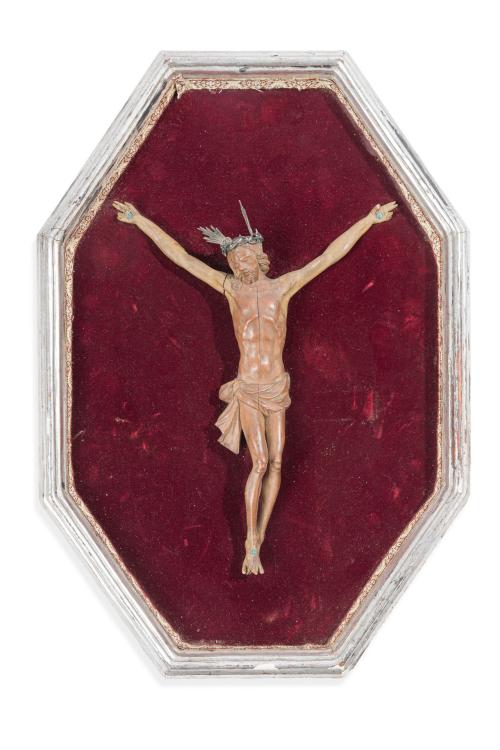 Cristo crucificado en madera tallada, sobre terciopelo rojo